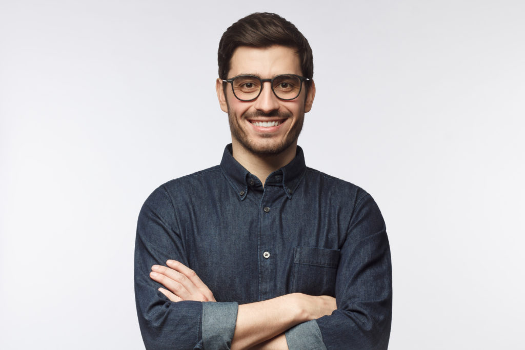 Confident guy standing with arms crossed, smiling, ready to help, isolated